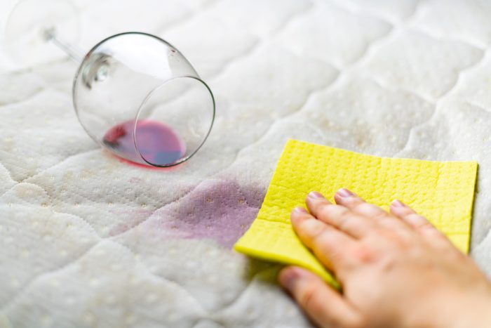 Spilt Red wine on a sofa being cleaned using a yellow sponge